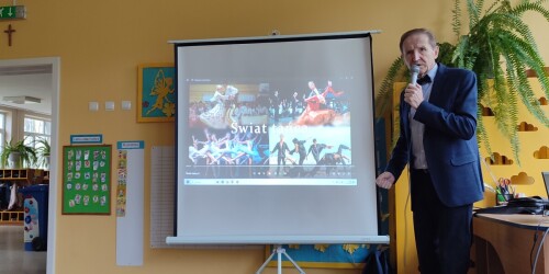 Mężczyzna wyświetla dzieciom prezentację multimedialną pod tytułem Świat tańca