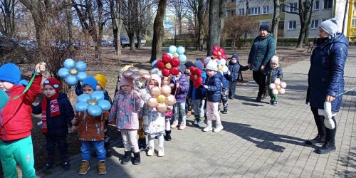 Spacer w okolicy przedszkola z wiosennymi atrybutami takimi jak kwiaty i balony